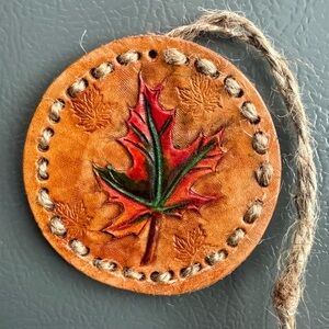 Handmade hand-carved maple leaf in leather on wood backing with magnet backing